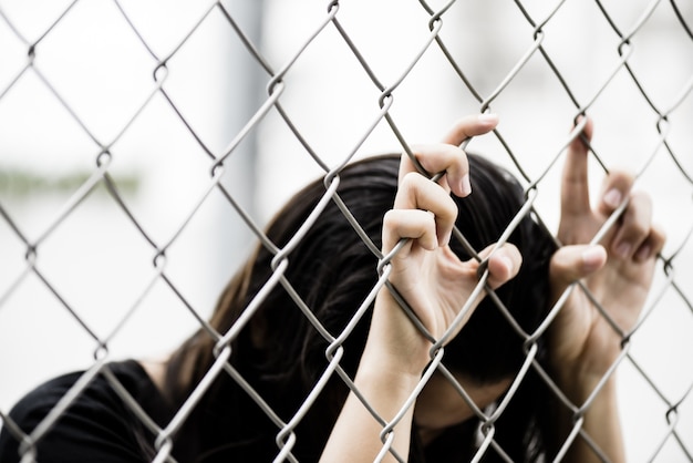 De handholding van de vrouw op de omheining van de kettingsverbinding voor vrijheid