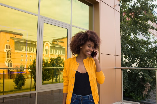 De Happy African American vrouw op straat praten aan de telefoon