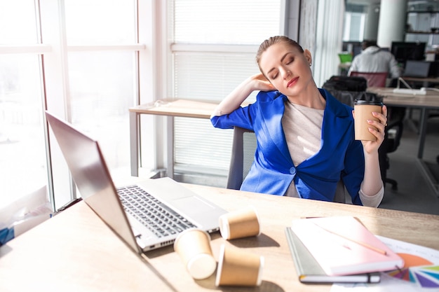 De hardwerkende vrouw zit aan tafel en rust uit