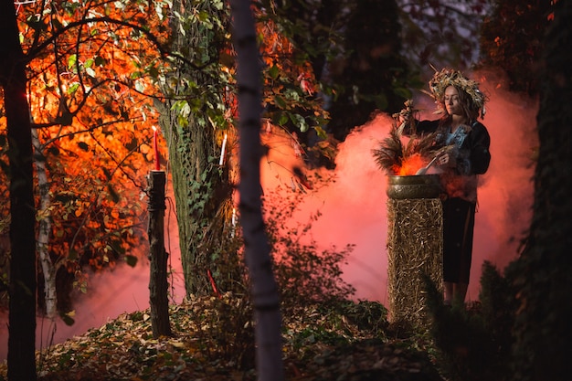 De heksenvrouw maakt betovering met ketel op het bos