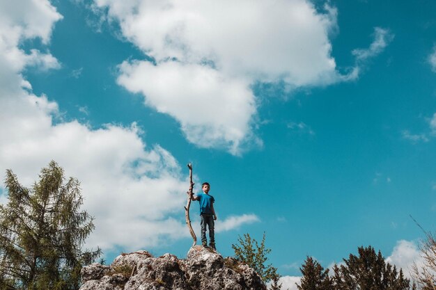 Foto de hele lengte van de jongen die op een rotsformatie tegen de lucht staat