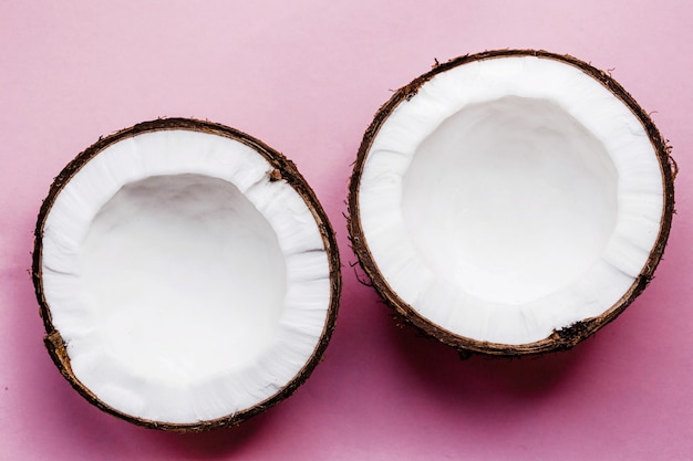 De helft van een kokosnoot ligt op een roze achtergrond