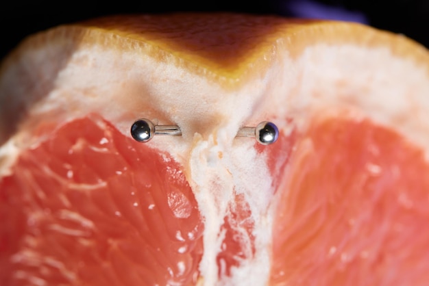 De helft van grapefruit met verticale barbell piercing op een achtergrond
