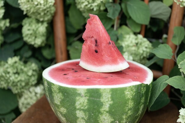 De helft van rijpe rode watermeloen en driehoekig plakje sappig rijp fruit op de bovenste rijpe watermeloen