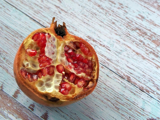 De helft van sappig roze granaatappelfruit met rijpe zaden op een houten tafel