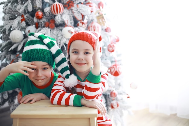 De helpers van de kerstman. Schattige kinderen in kerst elf kostuums in een kamer prachtig versierd voor Kerstmis. Tijd van wonderen. Cadeautjes van Sinterklaas.