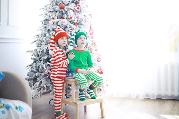 De helpers van de kerstman. Schattige kinderen in kerst elf kostuums in een kamer prachtig versierd voor Kerstmis. Tijd van wonderen. Cadeautjes van Sinterklaas.