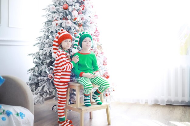 De helpers van de kerstman. schattige kinderen in kerst elf kostuums in een kamer prachtig versierd voor kerstmis. tijd van wonderen. cadeautjes van sinterklaas.