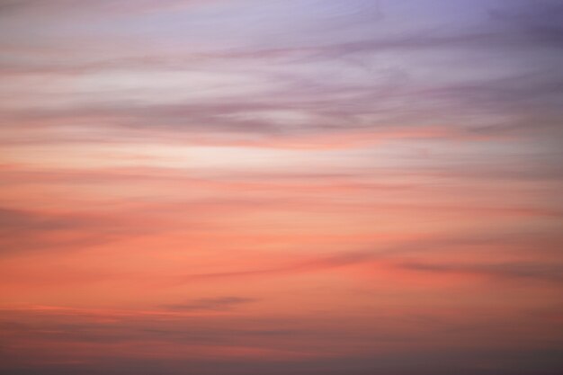 Foto de hemel bij zonsondergang met veren wolken. de kleur van de lucht verandert van paars naar donkeroranje.