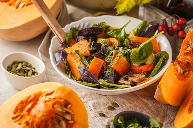 De herfstsalade van gebakken pompoen, biet, courgette en wortelen. Gezond veganistisch eten concept.