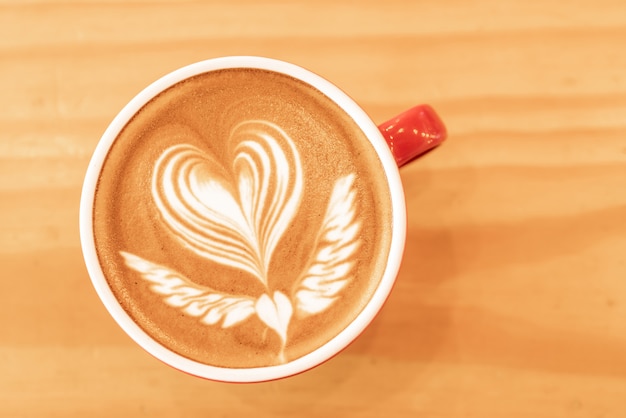 Foto de hete cappuccino van de kunstkoffie in een kop op houten lijstachtergrond met exemplaarruimte