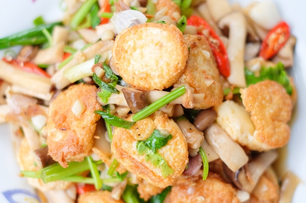 Foto de hete geroerbakte tofu en het varkensvlees en de paddestoel met zwarte bonensaus dienen op witte schotel die op bruine lijst wordt geplaatst - eigengemaakt voedselconcept.