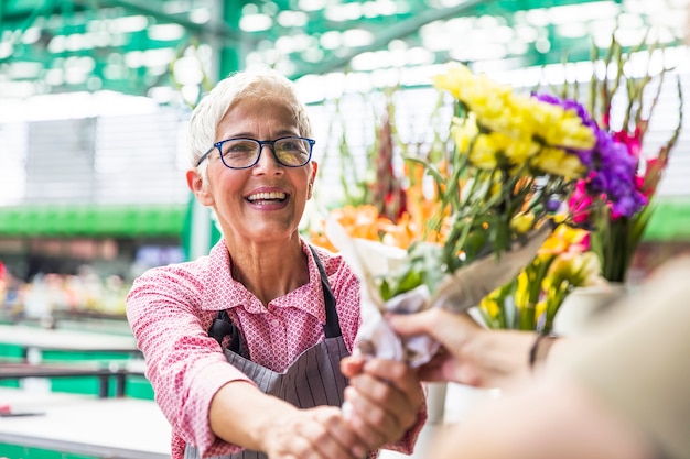 De hogere bloemen van de vrouwenverkoop op lokale bloemmarkt