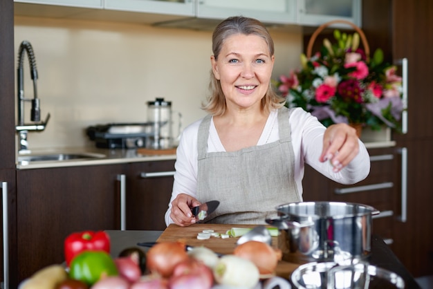 De hogere vrouw kookt thuis