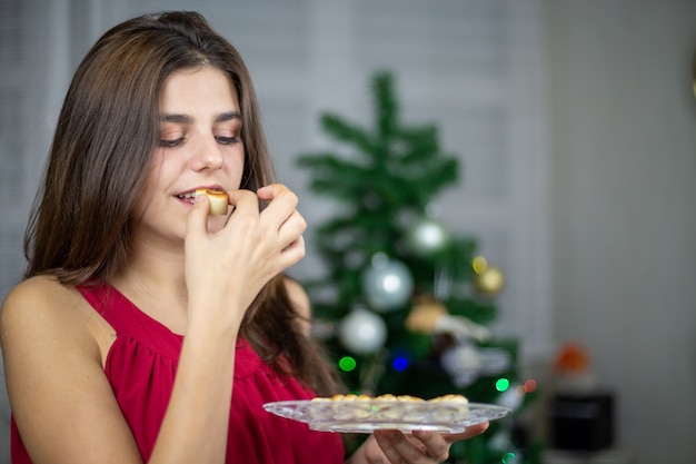 De holdingsplaat van de vrouw met heerlijke marsepeinsnoepjes en het eten bij Kerstmis