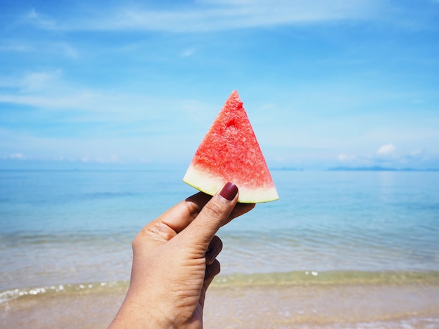 De holdingswatermeloen van de selfiehand over de achtergrond van het de zomerstrand.