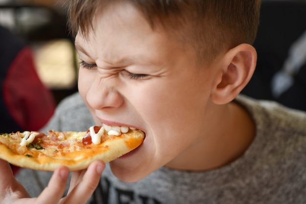 De hongerige tiener eet pizza bij pizzeria