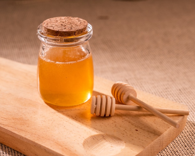 de honingpot op een houten bord in de buurt van honing lepel