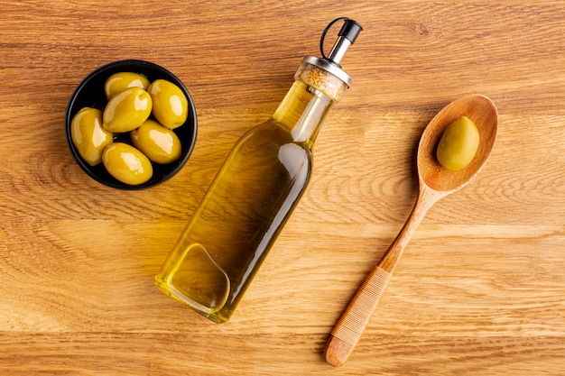 Foto de houten lepel van de olijfoliefles en gele olijven