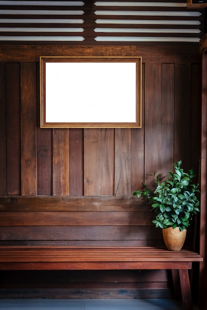 De houten omlijsting hangt op houten muurachtergrond met installatievaas op stoel.