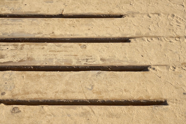 De houten planken van de oude brug zijn bedekt met zand als achtergrond