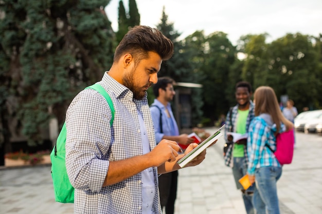 De Indiase student staat buiten en houdt een stapel boeken vast