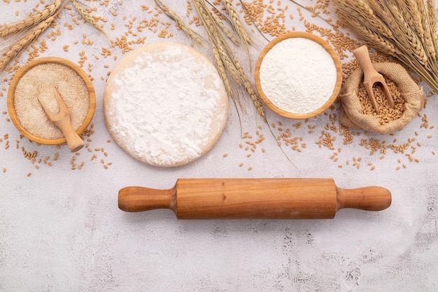 Foto de ingrediënten voor zelfgemaakt pizzadeeg met tarweoren, tarwebloem en tarwekorrels op een witte betonnen ondergrond