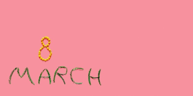 De inscriptie 8 maart gele bloemen en groene mimosa bladeren ligt op de roze achtergrond van de internationale Vrouwendag vakantie lente horizontale brede banner zachte focus vrije ruimte voor tekst