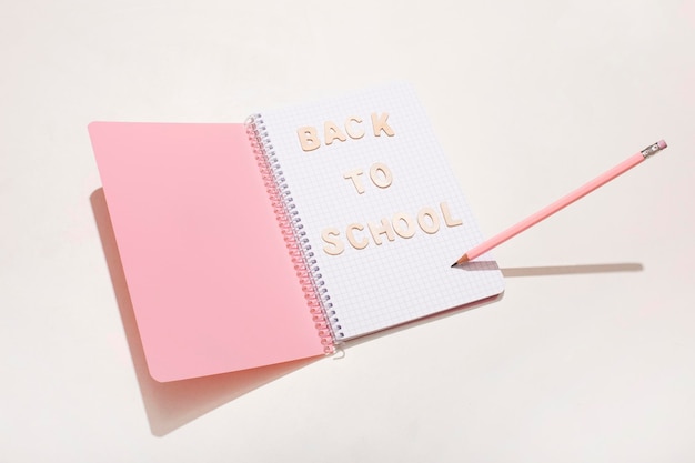 De inscriptie terug naar school op een roze blocnote met een potlood