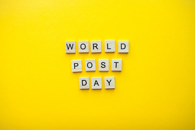 Foto de inscriptie wereld postdag van houten blokken op een felgele achtergrond