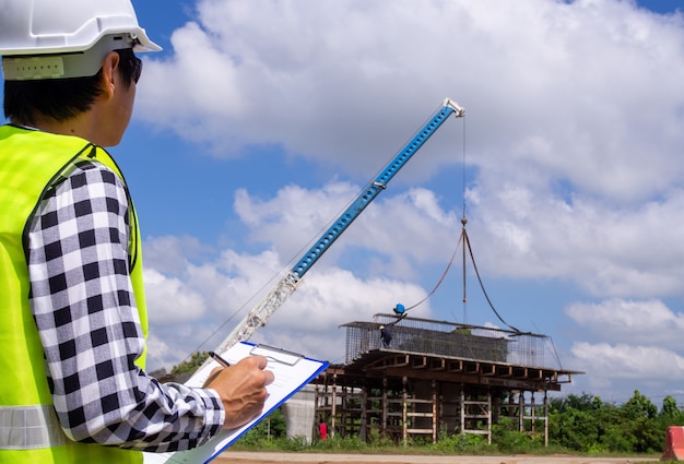 De inspecteurs of ingenieurs controleren het werk van het aannemersteam om een brug over de weg te bouwen.