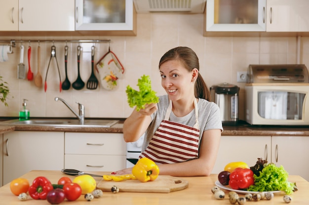 De jonge aantrekkelijke vrouw in een schort met slablad in de keuken. Dieet concept. Gezonde levensstijl. Thuis koken. Eten koken.