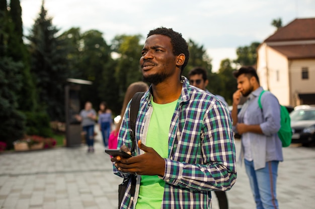 De jonge Afrikaanse student gebruikt navigatie op een smartphone