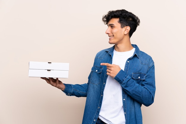 De jonge Argentijnse pizza's van de mensenholding over geïsoleerde muur die aan de kant richten om een product te presenteren