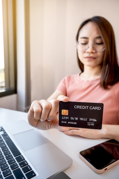 De jonge Aziatische hand die van de consumentvrouw een creditcard houdt