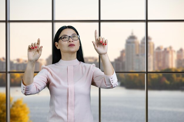 De jonge aziatische vrouw communiceert met beide handen met het onzichtbare virtuele scherm