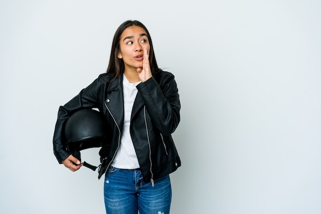 De jonge Aziatische vrouw die een motorhelm houdt zegt een geheim heet remmend nieuws en kijkt opzij