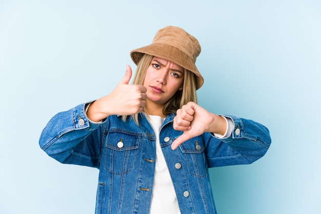 De jonge blonde Kaukasische vrouw isoleerde neer tonend duimen en duimen, kies concept