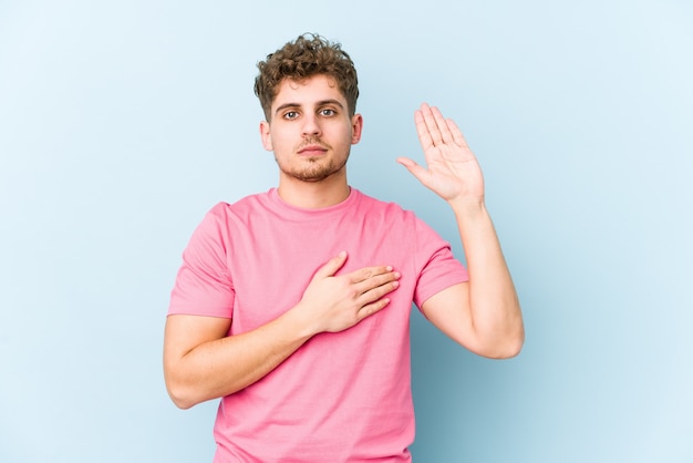 De jonge blonde krullende haar Kaukasische mens isoleerde het nemen van een eed, die hand op borst zetten.