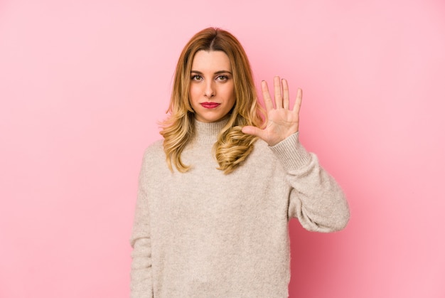 De jonge blonde leuke vrouw die een sweater draagt isoleerde glimlachend vrolijk tonend nummer vijf met vingers.