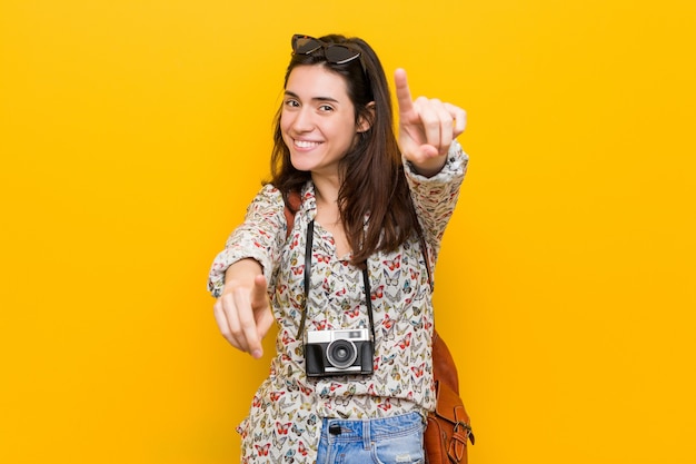 De jonge brunette vrolijke glimlach van de reizigersvrouw wijst naar voren.