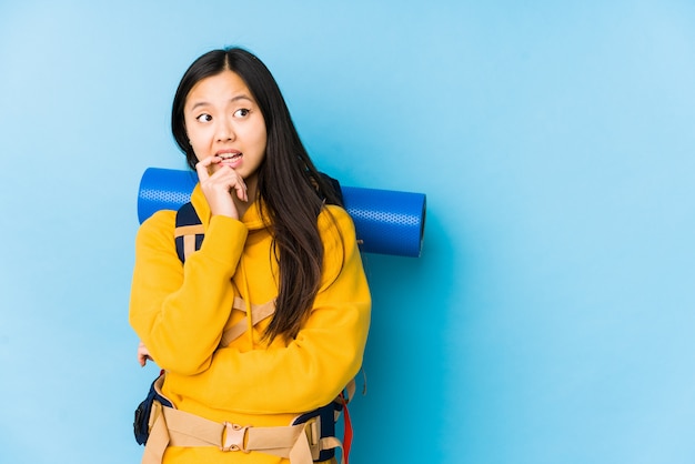 De jonge Chinese backpackervrouw isoleerde ontspannen denkend aan iets bekijkend een exemplaarruimte.