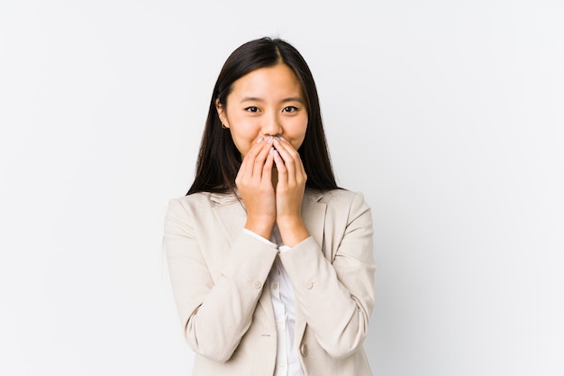 De jonge Chinese bedrijfsvrouw isoleerde lachend over iets, behandelend mond met handen.