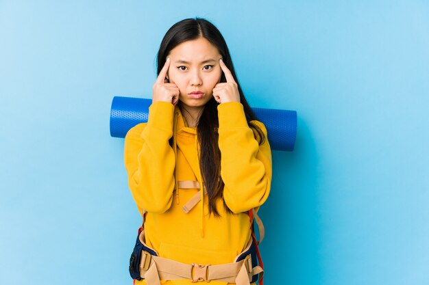 De jonge Chinese geïsoleerde backpackervrouw concentreerde zich op een taak, houdend wijsvingers die hoofd richten.