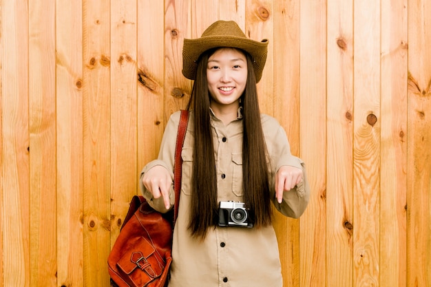 De jonge Chinese reizigersvrouw wijst neer met vingers, positief gevoel.