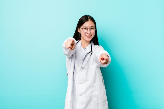 De jonge Chinese vrolijke glimlach die van de artsenvrouw naar voorzijde wijst.