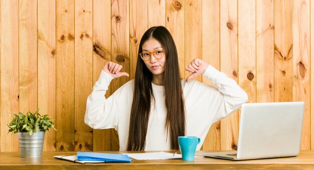 De jonge Chinese vrouw die op haar bureau bestudeert voelt trots en zelfverzekerd, te volgen voorbeeld.