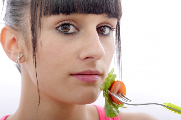 De jonge donkerbruine vrouw eet salade, omhoog sluit