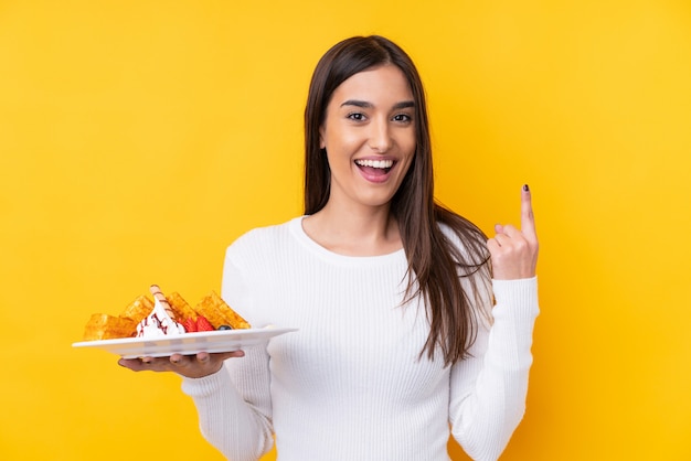 De jonge donkerbruine wafels van de vrouwenholding over geïsoleerde muur die een groot idee benadrukken