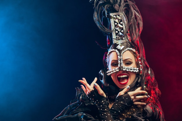 De jonge gelukkig lachende mooie danseres met carnaval jurken poseren op zwarte studio achtergrond